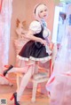 A woman in a maid outfit sitting on a chair.